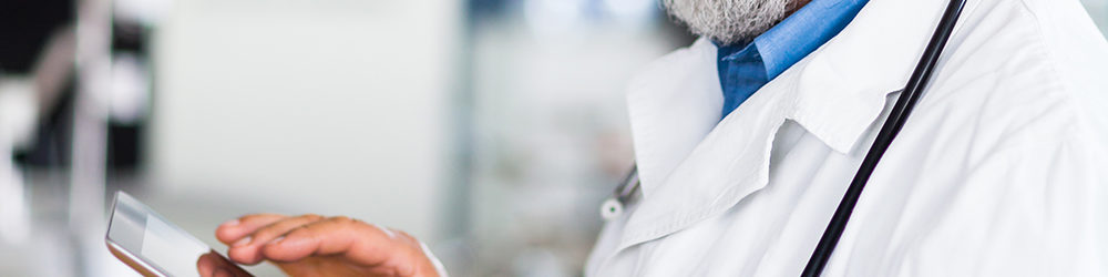 Senior doctor using his tablet computer to manage patients and billing.